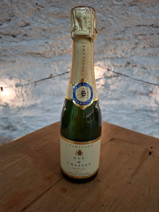half bottle of Guy de Chassey champagne on a wooden surface with a textured wall background