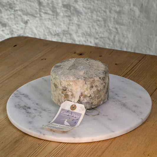 Round of Yoredale cheese on a marble platter with a rustic background