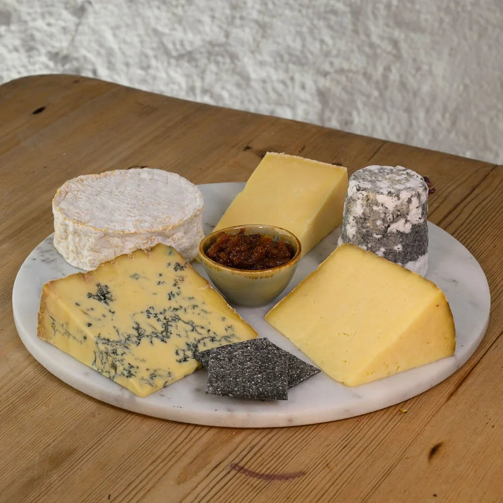 Assorted cheeses on a marble platter with a wooden background