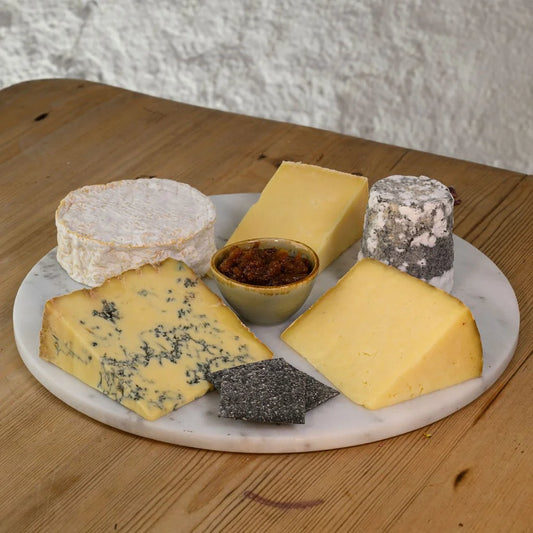 Assorted cheeses on a marble platter with a wooden background