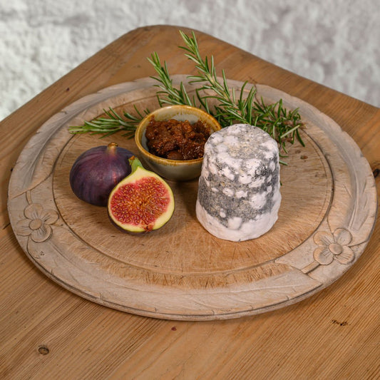 Wooden board with Dorstone, figs, and herbs on a wooden surface
