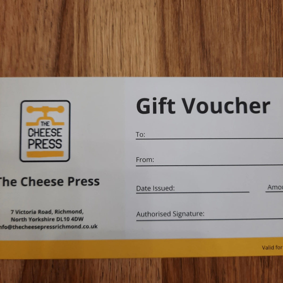 Gift voucher from The Cheese Press on a wooden surface