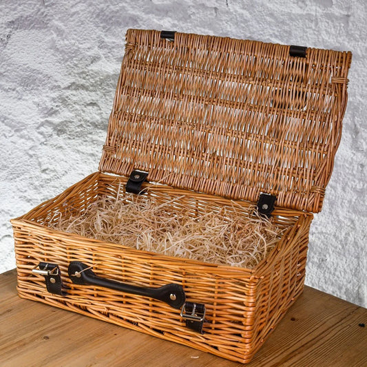 Wicker picnic basket with black handles on a wooden surface