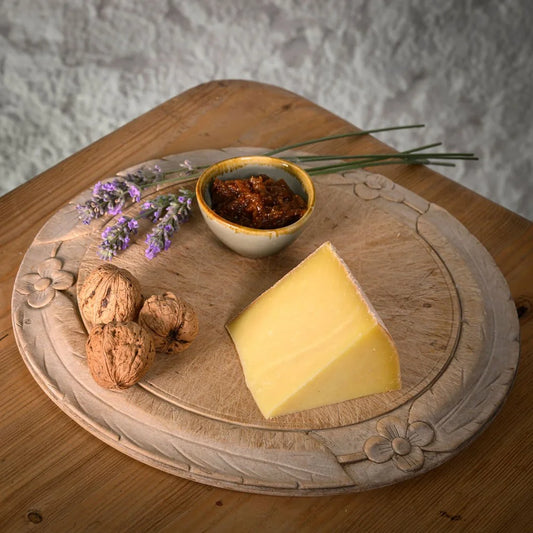 Wooden platter with Kit Calvert cheese, nuts, and a small bowl on a rustic background