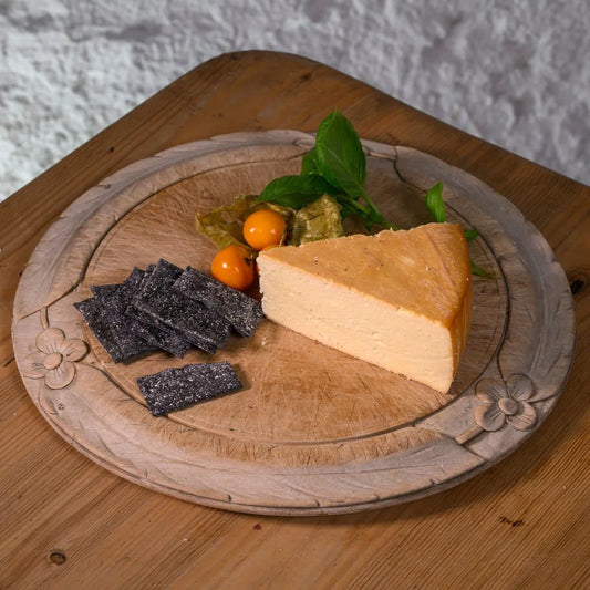 Slice of smoked swaledale cheese with crackers and persimmon on a decorative wooden board.