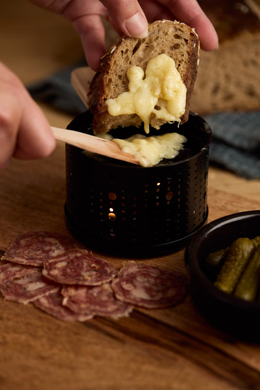 Raclette cheese melted onto bread with charcuterie and pickles