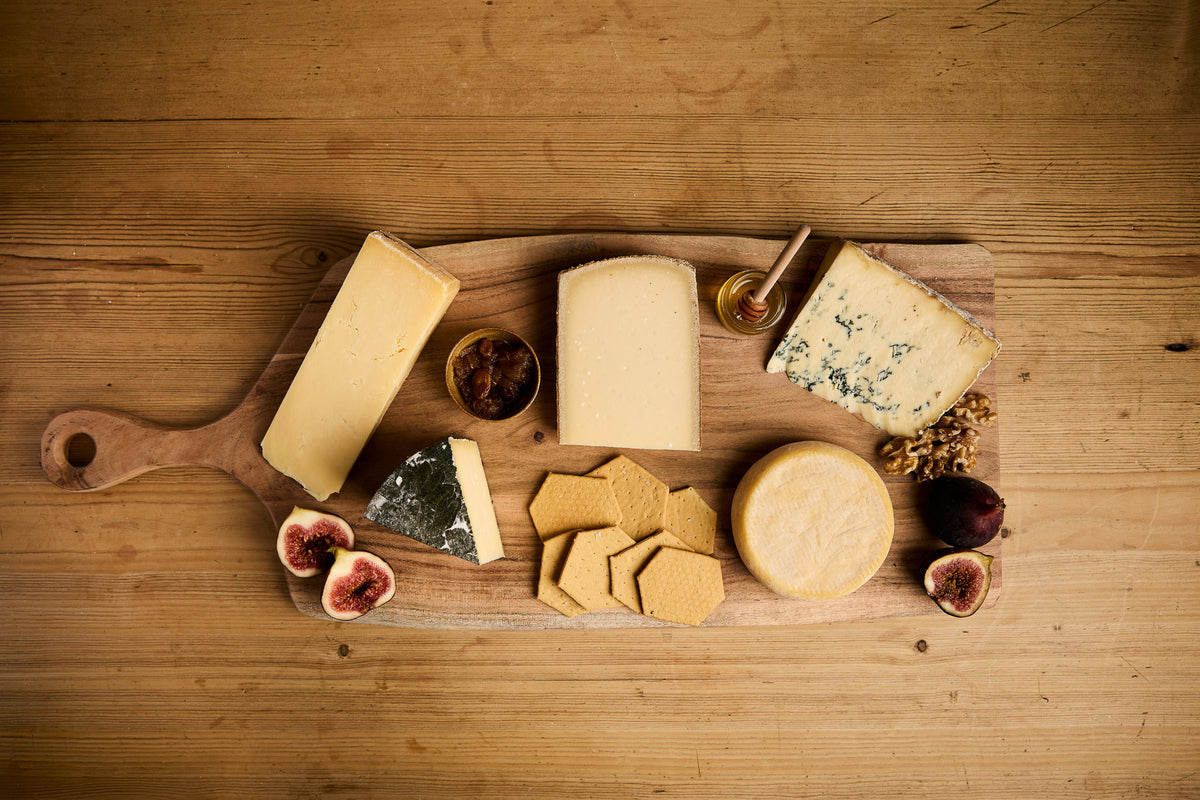 Selection of artisan cheeses with crackers, figs, walnuts and honey on a wooden cheeseboard