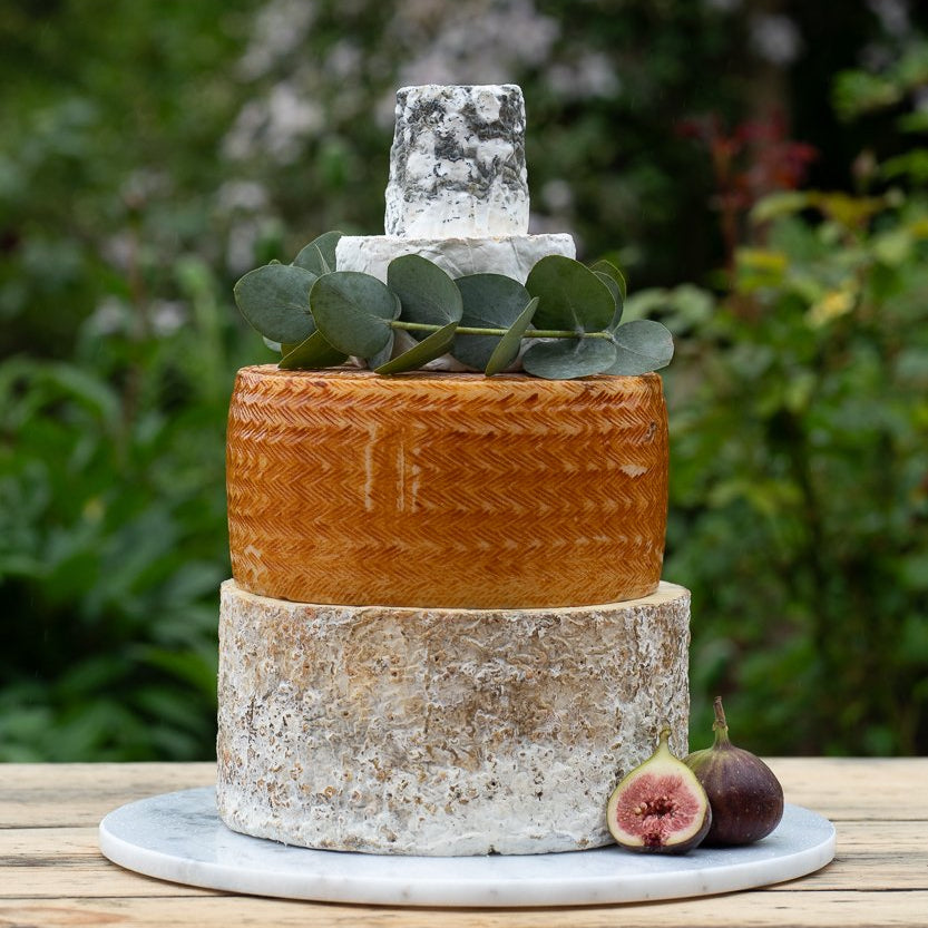 Four-tier celebration cheese cake decorated with eucalyptus and figs